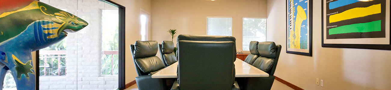 A long hallway featuring a green table surrounded by chairs, creating a welcoming and spacious atmosphere.